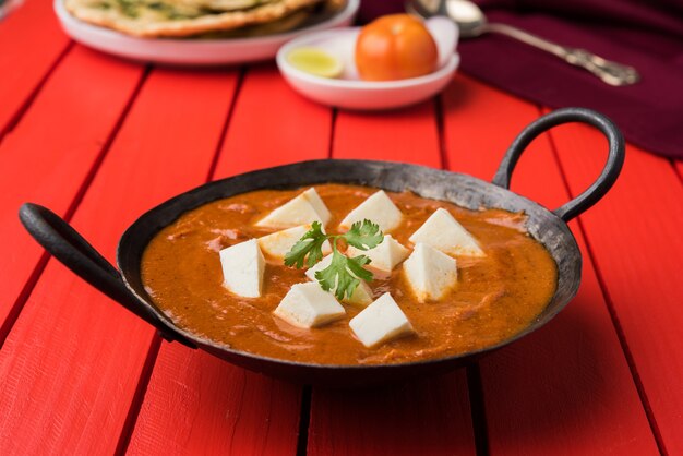 Paneer Butter Masala lub Cheese Cottage Curry, popularne indyjskie menu na lunch i kolację serwowane w Karahi z Naan lub Roti na nastrojowym tle, selektywne skupienie