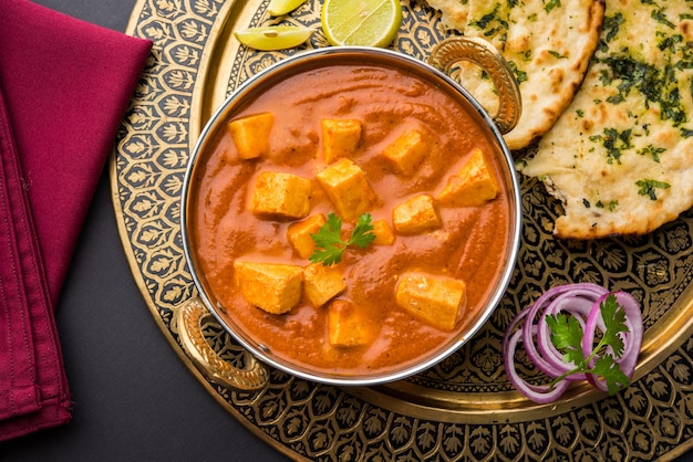 Paneer Butter Masala lub Cheese Cottage Curry, popularne indyjskie menu na lunch i kolację serwowane w Karahi z Naan lub Roti na nastrojowym tle, selektywne skupienie