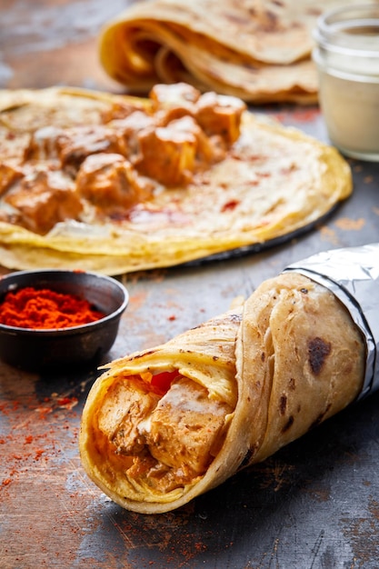 Paneer Makhani paratha roll kathi shawarma wrap z sosem zanurzeniowym na białym tle na tle widok z boku indyjskiego fastfoodu