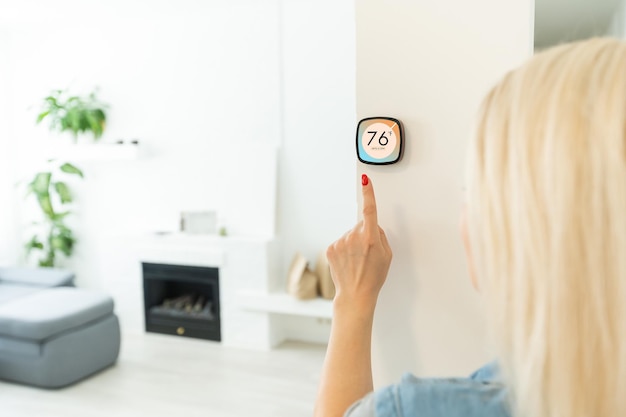 Zdjęcie panel sterowania termostatem inteligentnego domu na ścianie do zimowego baneru temperatury w domu. energooszczędne dotknięcie ręką w celu regulacji temperatury ogrzewania w salonie.