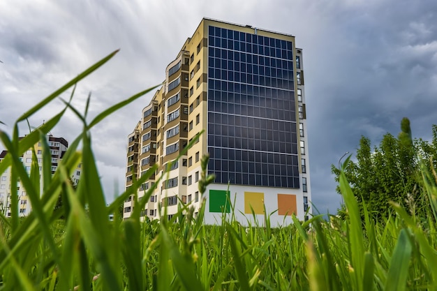 Panele słoneczne na ścianie wielopiętrowego budynku na tle zielonych drzew Odnawialna energia słoneczna