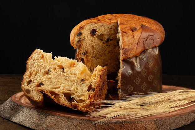 Panettone z pokrojonym tradycyjnym kawałkiem świątecznego jedzenia z czarnym tłem.