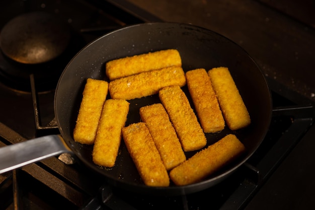 Panierowane paluszki rybne na patelni Przygotowanie mrożonych paluszków rybnych Fast food Ciemne tło