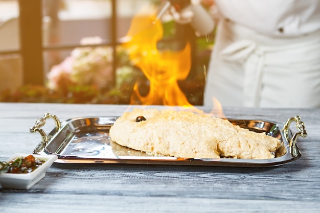 Zdjęcie panierowane ryby spalające się na tacy. surowa ryba pokryta solą. specjalny przepis na rybę dorado. przygotowanie owoców morza w restauracji.