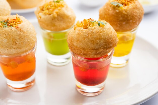 Zdjęcie panipuri shot lub golgappa shots różne smaki wody podawane w małych szklankach z nadziewaną puri indyjską przekąską przystawkową