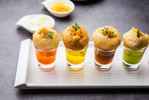 Panipuri shot lub Golgappa Shots różne smaki wody podawane w małych szklankach z nadziewaną puri indyjską przekąską przystawkową