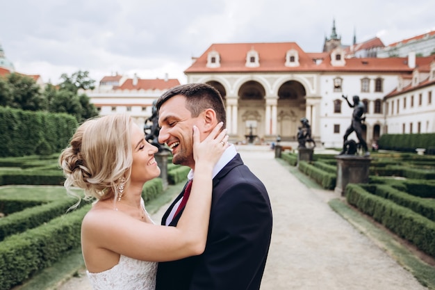 Panna młoda i pan młody przytulają się, całują na zewnątrz w dniu ślubu, spacer młodej pary po Pradze, walentynki