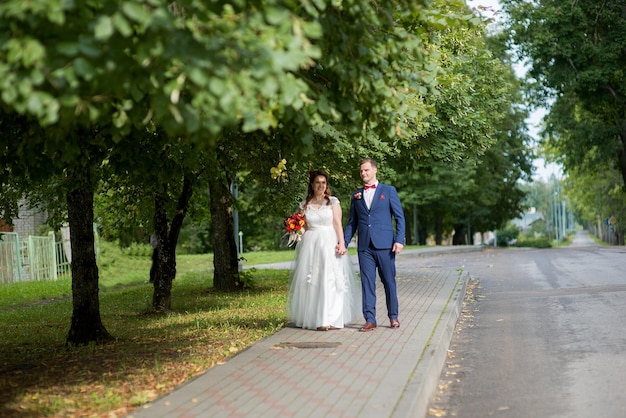 Panna młoda i pan młody spacerują po parku.