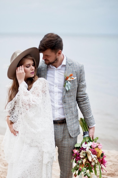 Panna młoda i pan młody stoją na plaży podczas ceremonii ślubnej