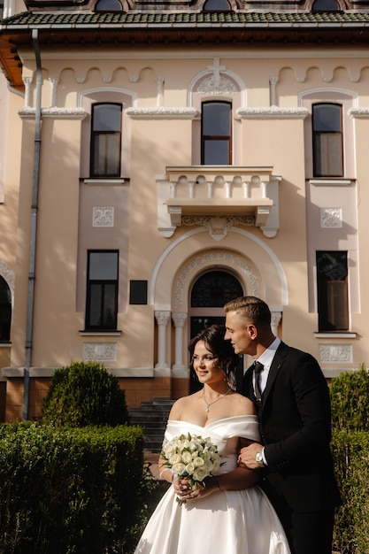 Panna młoda i pan młody stoją przed różowym budynkiem.