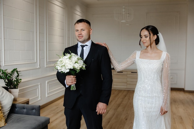 Panna młoda i pan młody trzymają kwiaty w rękach.