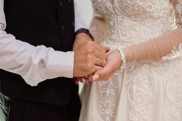 Panna młoda i pan młody trzymający się za ręce w dniu ślubu Zbliżenie