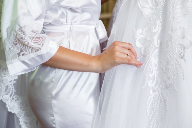 Panna Młoda trzyma w rękach piękną suknię ślubną