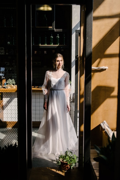Panna młoda w białej ślubnej sukni pozuje indoors