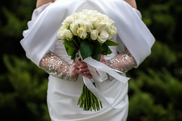 Zdjęcie panna młoda w białej sukni ślubnej trzyma bukiet białych kwiatów piwonie róż ślub panna młoda i pan młody delikatny bukiet powitalny piękna dekoracja ślubów z listkami