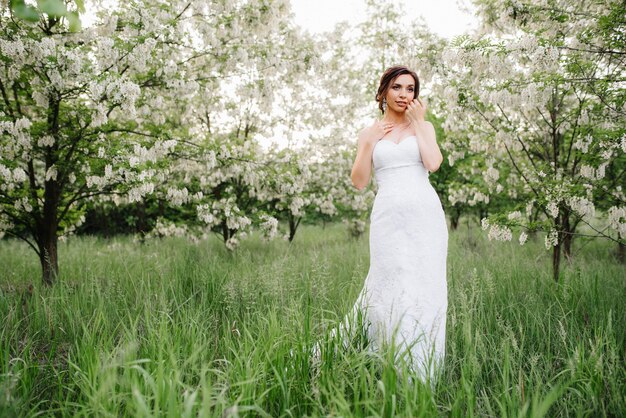 Panna młoda w białej sukni z dużym wiosennym bukietem w zielonym lesie
