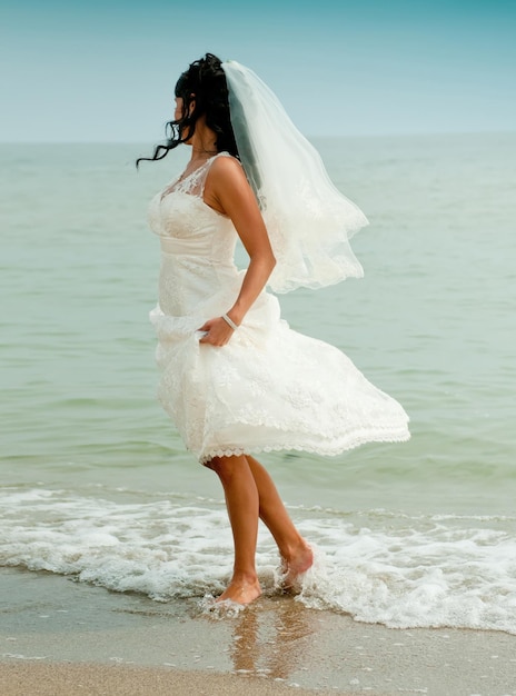 Panna młoda w białej sukni zrelaksowana na wybrzeżu