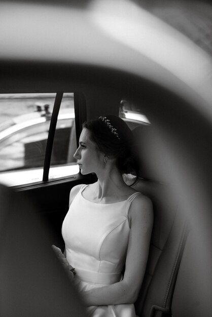Zdjęcie panna młoda z czarnym samochodem w pobliżu szklanego drapacza chmur