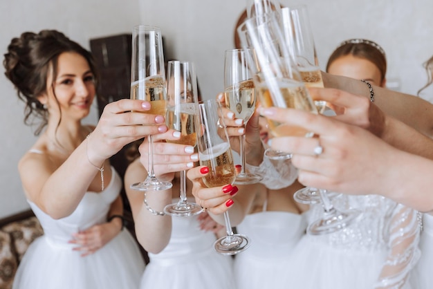 Panna młoda z wesołymi dziewczynami na ślubie piją szampana z kieliszków panna młoda i dziewczyny