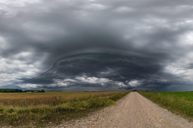 Panorama czarnego nieba w tle z burzowymi chmurami grzmot z przodu nad żwirową drogą