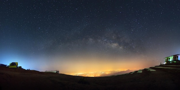 Panorama galaktyki Drogi Mlecznej i światła miasta w Phutabberk Phetchabun w TajlandiiFotografia długoczasowa ze ziarnem