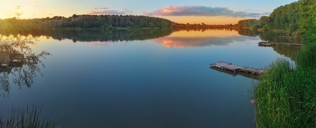 Panorama jeziora z pomostem rybackim o zachodzie słońca. Fotografia lotnicza