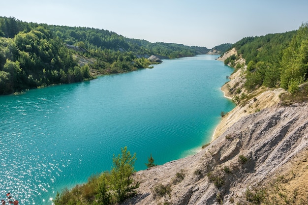 Panorama kredy na wapiennym wybrzeżu ogromnego turkusowego jeziora lub rzeki w pobliżu lasu Kamieniołom kredy wypełniony wodą