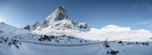 Panorama ośnieżonego pasma górskiego z błękitnym niebem i autostradą w Nordland