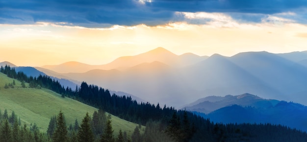 Panorama pasma górskiego ze wzgórzami, słońcem, chmurami i niebem o zachodzie słońca