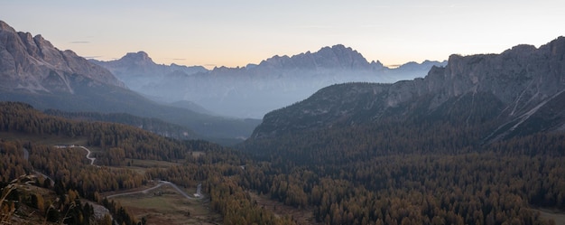 Zdjęcie panorama pięknej doliny alpejskiej przed wschodem słońca z mgłą i złotymi larczami dolomity włoskie