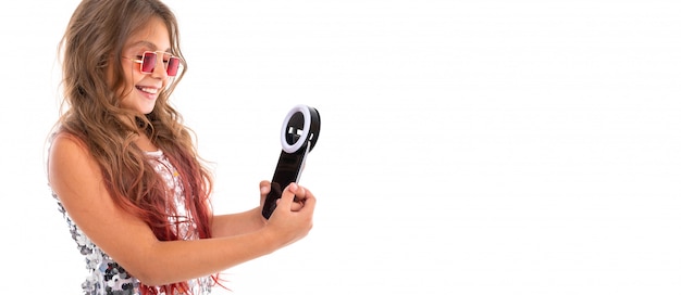 Panorama Uśmiechnięta Dziewczyna Trzyma Czarnego Telefon Komórkowego Z Diodą Dla Selfie Odizolowywającego W Kwadratowych Czerwonych Okularach Przeciwsłonecznych