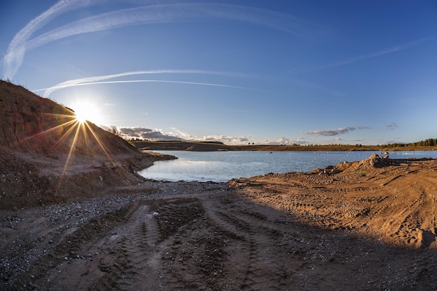 Panorama w pobliżu kamieniołomu zalanego wodą do wydobywania piasku w wieczornym słońcu