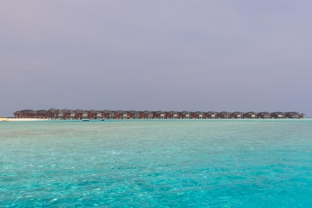 Panorama willi na wodzie (Bungalows) i drewniane molo na tropikalnej plaży na Malediwach w lecie