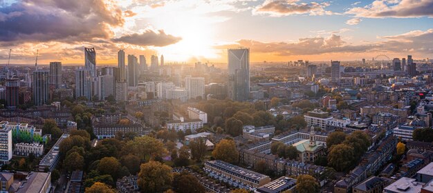 Panorama z lotu ptaka dzielnicy finansowej Londynu z wieloma kultowymi drapaczami chmur w pobliżu Tamizy o zachodzie słońca.