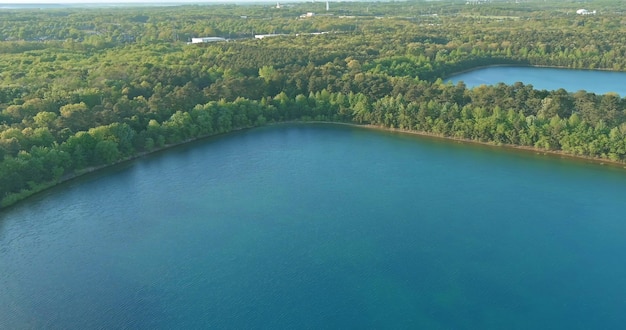 Panorama z lotu ptaka na zielony las między turkusową wodą jeziora