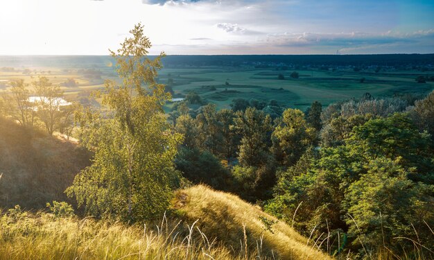 Zdjęcie panoramiczny krajobraz pól uprawnych ze wzgórza podczas zachodu słońca.