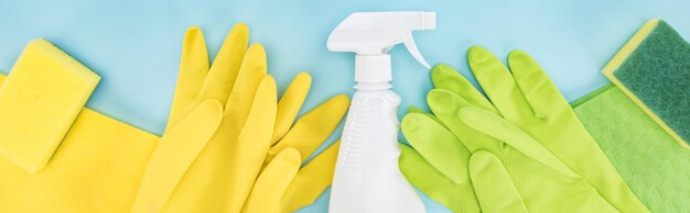 Zdjęcie panoramiczny strzał żółtych i zielonych gumowych rękawiczek gąbki szmaty i butelkę spray z detergentem na