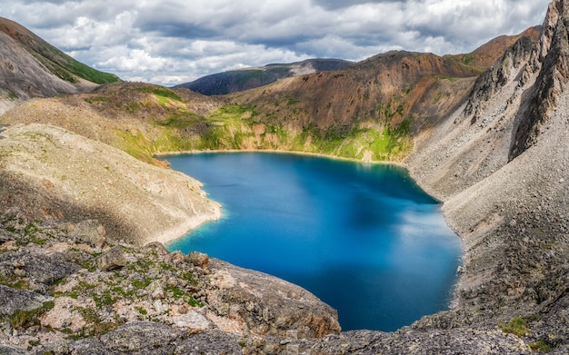 Panoramiczny widok na górskie jezioro na tle gór. Nastrojowy zielony krajobraz z jeziorem w dolinie wysokogórskiej. Wspaniała sceneria z górskim jeziorem w górskiej dolinie