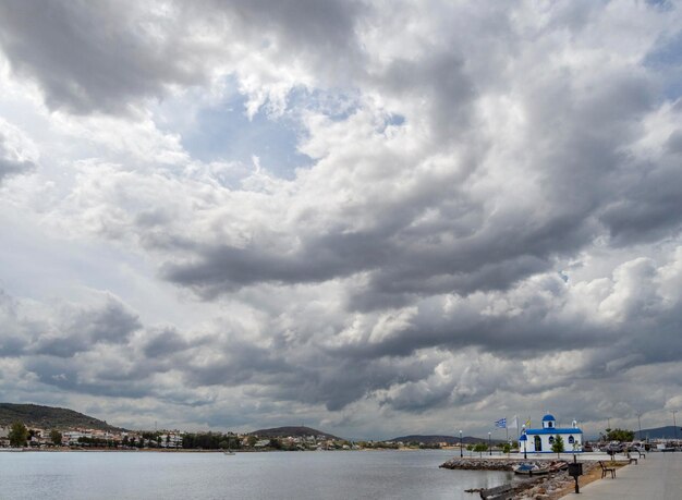 Panoramiczny widok na mały grecki kościółek z cumulusami na nabrzeżu na wyspie Evia Greece