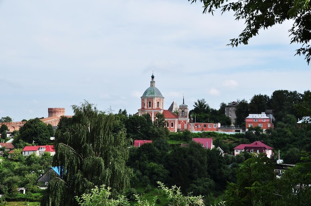 Panoramiczny widok na miasto. Widok na stary kościół i mury twierdzy. Prywatne domy wśród drzew.