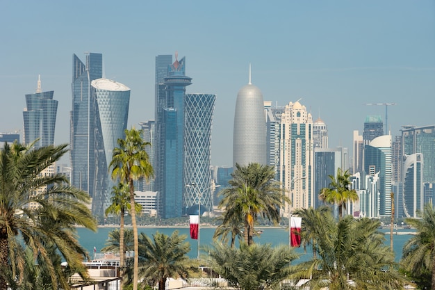 Panoramiczny widok na nowoczesną panoramę Doha przez niewyraźne palmy. Katar w słoneczny dzień.