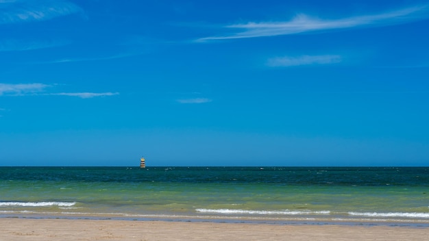 Panoramiczny widok na plażę z pilotem nawigacyjnym w morzu i niebo w tle o zachodzie słońca