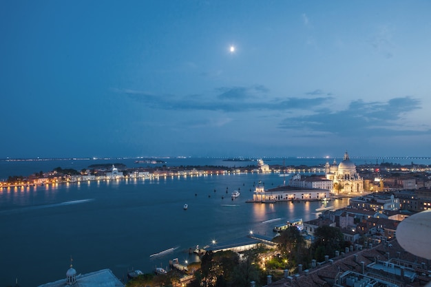 Panoramiczny widok na tradycyjną starą gondolę na Canal Grande z zabytkowym kościołem San Giorgio Maggiore na tle w pięknym złotym wieczornym świetle o zachodzie słońca latem, San Marco, Wenecja, Włochy.