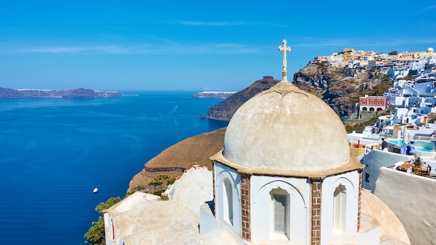 Panoramiczny widok na wyspę Santorini ze starożytnym greckim kościołem na wybrzeżu w mieście Fira (Thera), Grecja