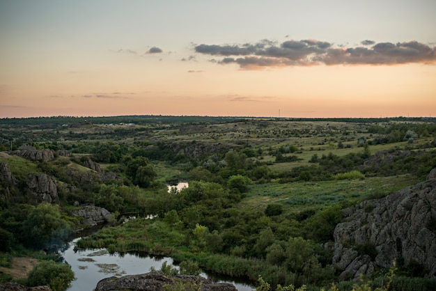 Zdjęcie panoramiczny widok na zielony krajobraz i rzekę o zachodzie słońca