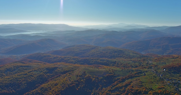 Panoramiczny widok z góry z niesamowitymi drzewami w fantastycznej porannej scenie słonecznej na jesiennych górach