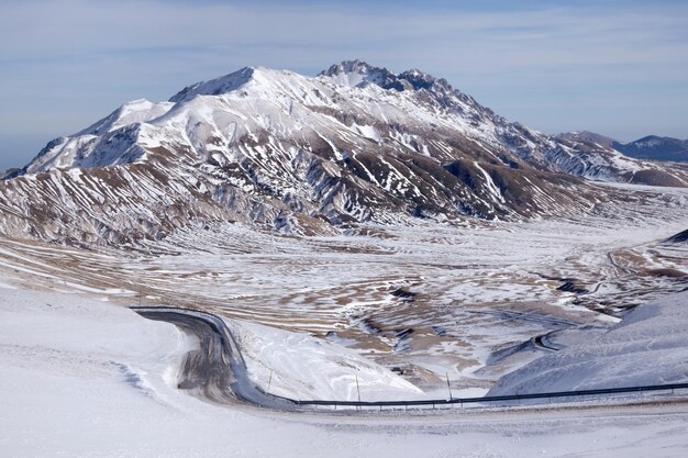 Panoramiczny widok zimowych gór w śniegu i serpentynowej drodze Campo Imperatore Gran Sasso Włochy