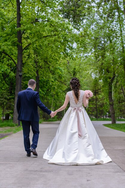 Państwo młodzi z ślubnym bukietem w parku