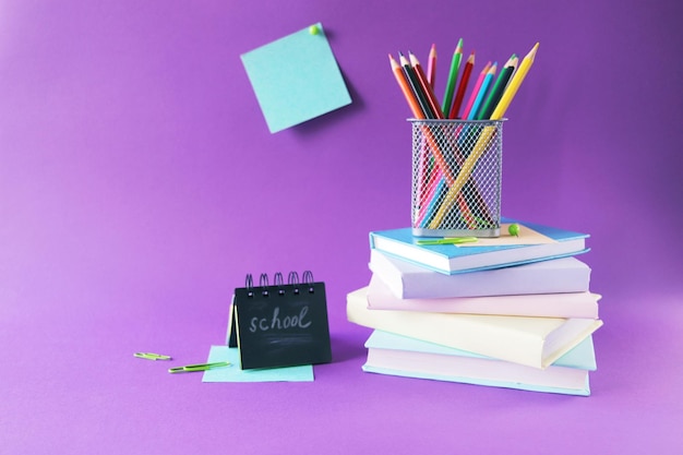 Papeteria i książki ołówki na fioletowym tle koncepcja uczenia się edukacji