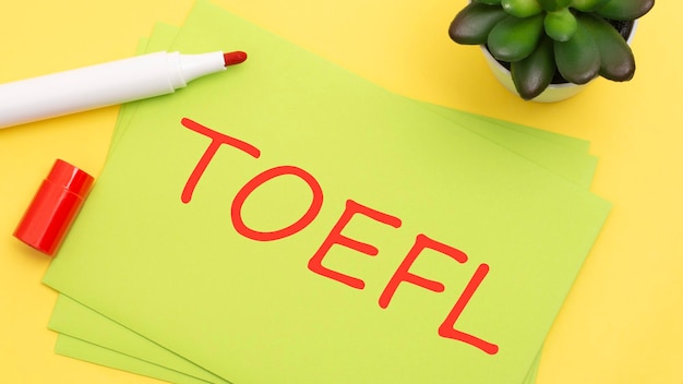 Papier z tekstem TOEFL na żółtym tle z papeterią